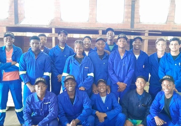 Group of students in blue uniforms posing indoors at a Mohair Classing training workshop.