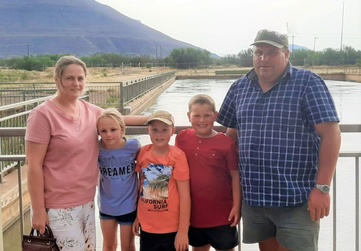 Willem and Soreta Wagener and their three children posing together on a bridge with a mountain in the background.