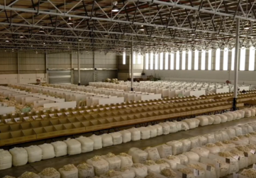Interior of a large warehouse filled with rows of bags filled with wool cuttings.